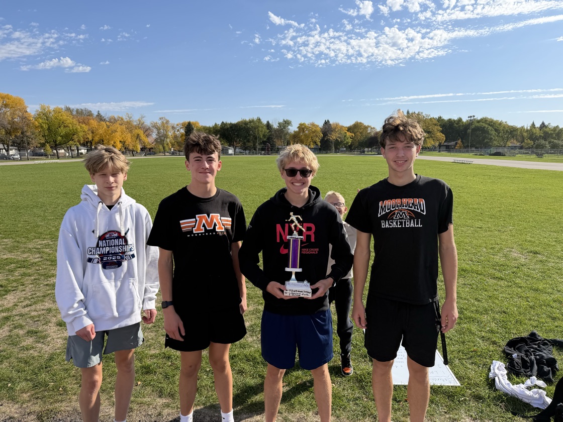 Four Moorhead high school runners standing on the grass with the Amazing Pace trophy